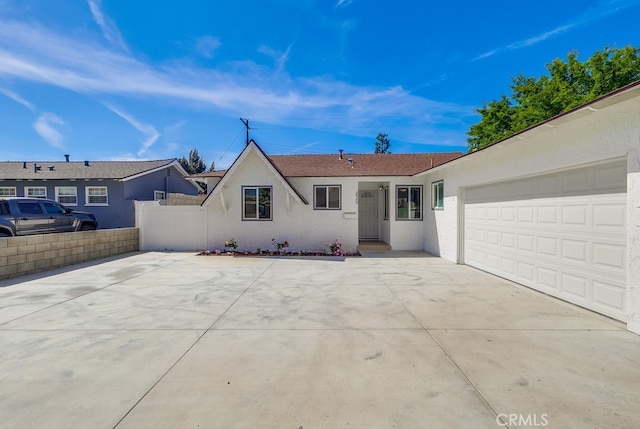 ranch-style house featuring a garage, fence, stucco siding, and concrete driveway