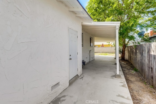 view of property exterior featuring a patio, fence, stucco siding, and an attached carport