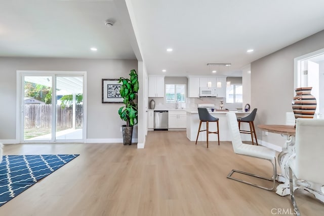living room featuring recessed lighting, baseboards, and light wood-type flooring