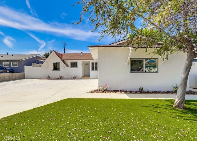 ranch-style house with a front lawn, stucco siding, and fence