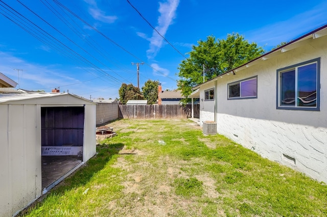 view of yard featuring an outbuilding, a storage shed, a fenced backyard, and an outdoor fire pit