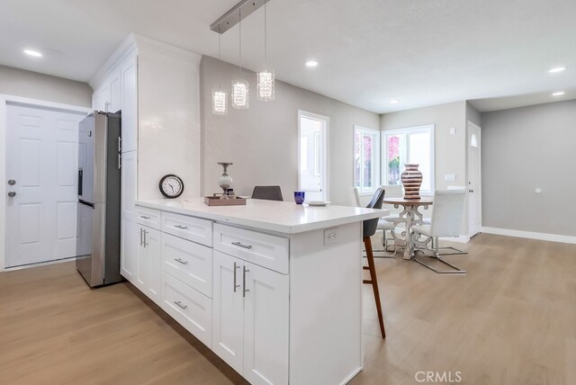 kitchen featuring a breakfast bar, a peninsula, light wood-style flooring, and stainless steel fridge with ice dispenser