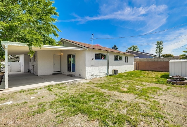 back of house with stucco siding, fence, cooling unit, and a yard
