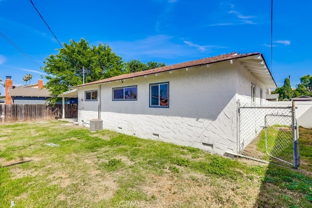view of side of property featuring crawl space, central AC unit, a lawn, stucco siding, and fence