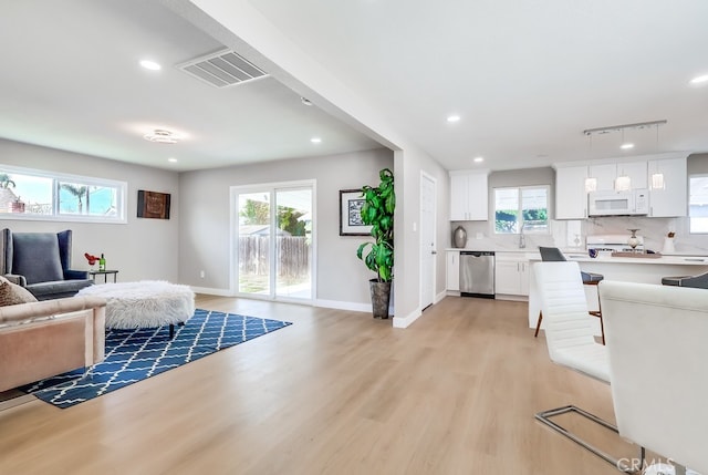 living area with light wood finished floors, recessed lighting, visible vents, and baseboards