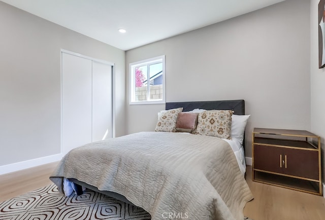 bedroom with baseboards, recessed lighting, wood finished floors, and a closet
