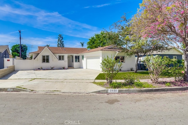 ranch-style home featuring stucco siding, fence, concrete driveway, and an attached garage