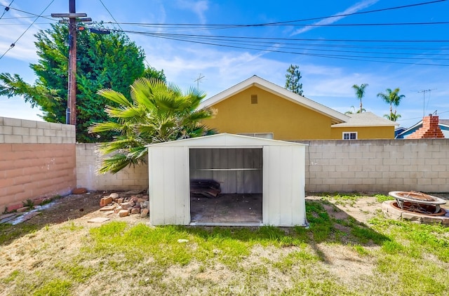 view of shed with a fenced backyard and an outdoor fire pit
