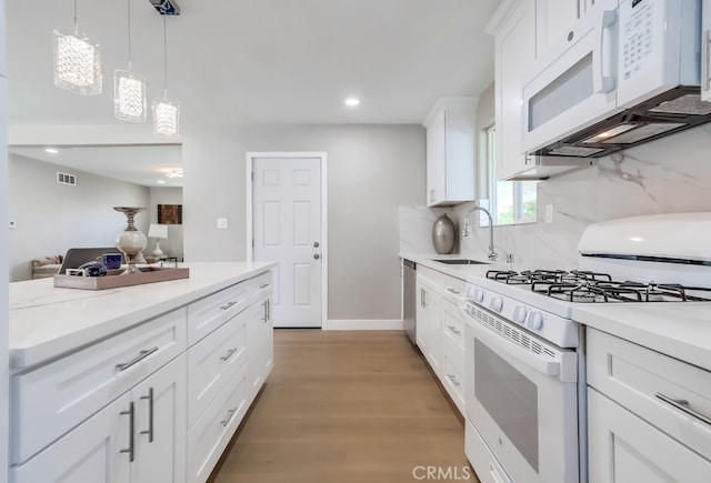 kitchen featuring recessed lighting, light wood finished floors, a sink, white appliances, and light countertops