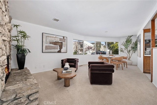 living room with baseboards, light colored carpet, visible vents, and a fireplace