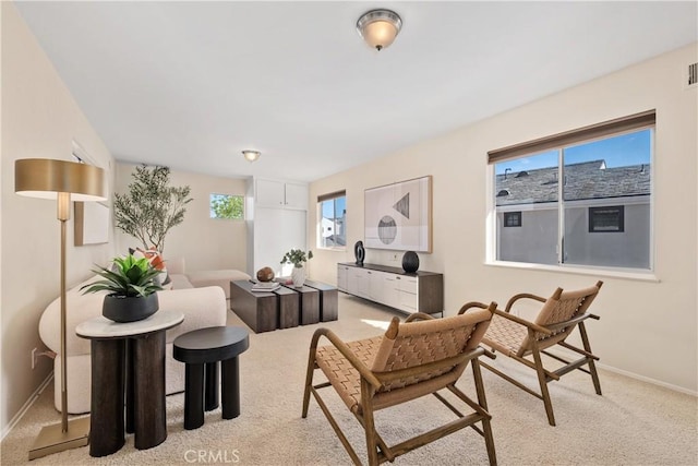 living area with light colored carpet, baseboards, and visible vents