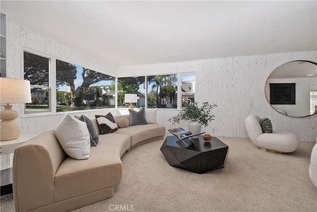 carpeted living area featuring wood walls