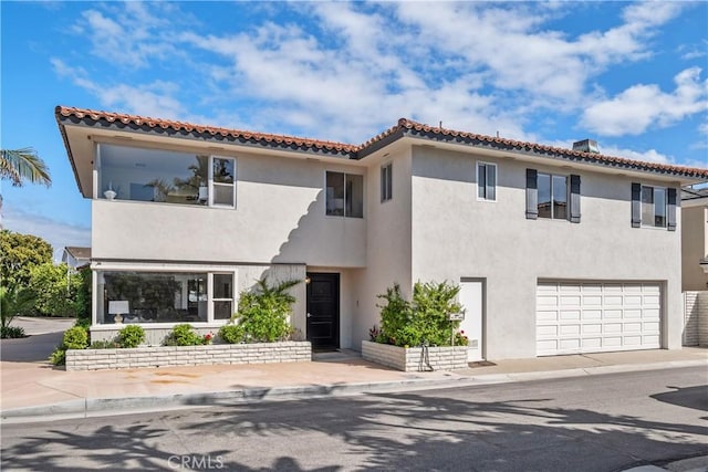 mediterranean / spanish home featuring a garage, stucco siding, and a tile roof