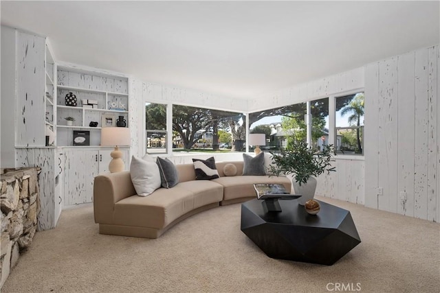 carpeted living room with wooden walls and a healthy amount of sunlight