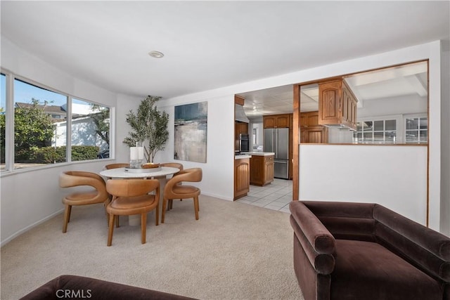 dining space with baseboards and light colored carpet