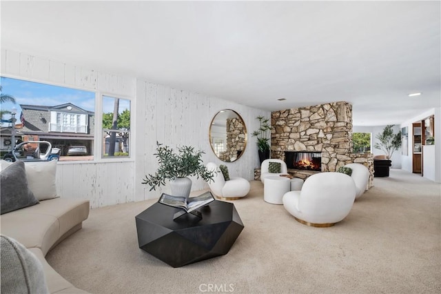 carpeted living area with a healthy amount of sunlight and a stone fireplace