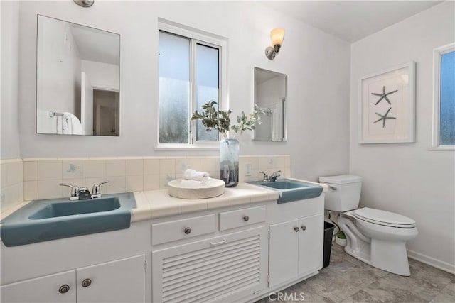 full bathroom featuring baseboards, a sink, toilet, and tasteful backsplash