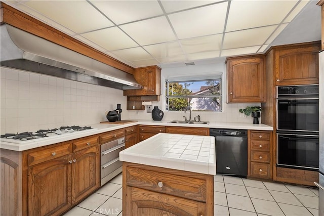kitchen with a sink, wall chimney exhaust hood, black appliances, and decorative backsplash