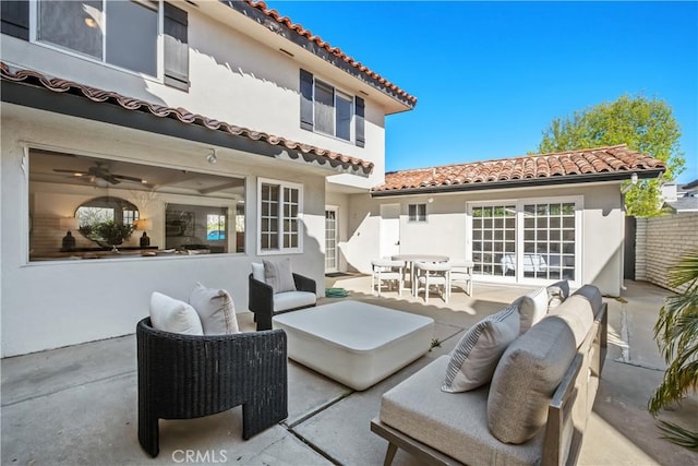 back of house featuring a patio area, stucco siding, a tile roof, and an outdoor hangout area