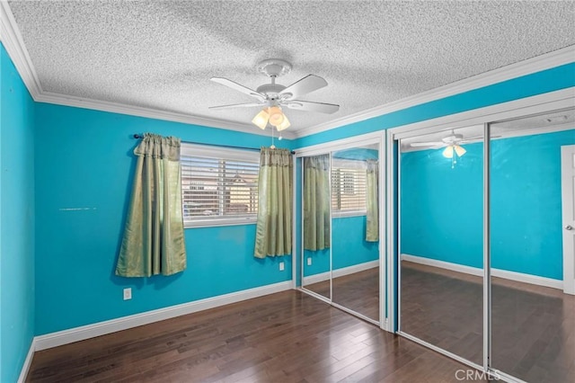 unfurnished bedroom featuring wood finished floors, a textured ceiling, crown molding, and multiple closets