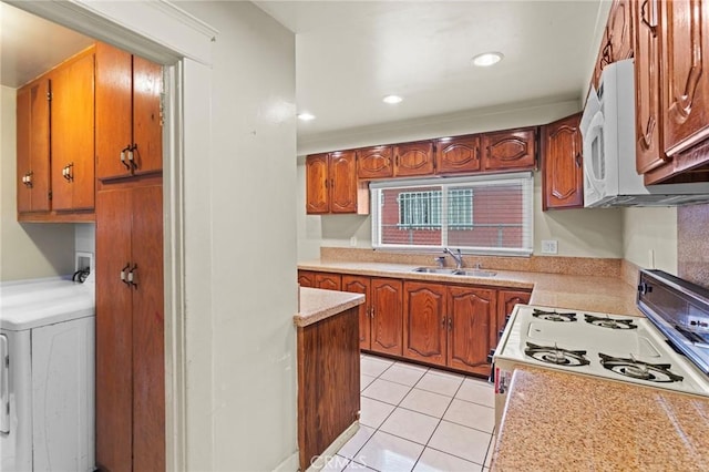 kitchen with a sink, light tile patterned floors, brown cabinetry, washer / dryer, and light countertops
