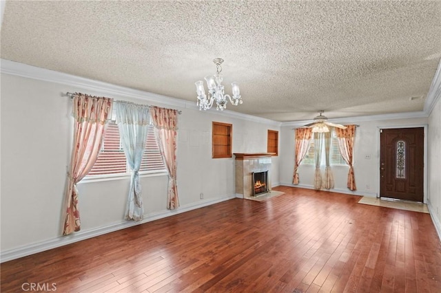 unfurnished living room featuring a fireplace with flush hearth, a textured ceiling, crown molding, hardwood / wood-style floors, and ceiling fan with notable chandelier