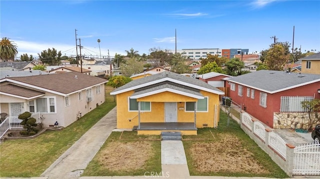 bungalow-style house with driveway, a residential view, stucco siding, a front yard, and fence