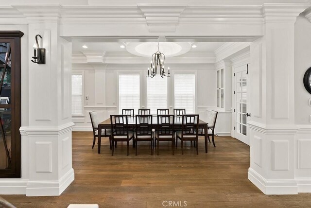 dining room with a chandelier, crown molding, dark wood-style flooring, and a decorative wall