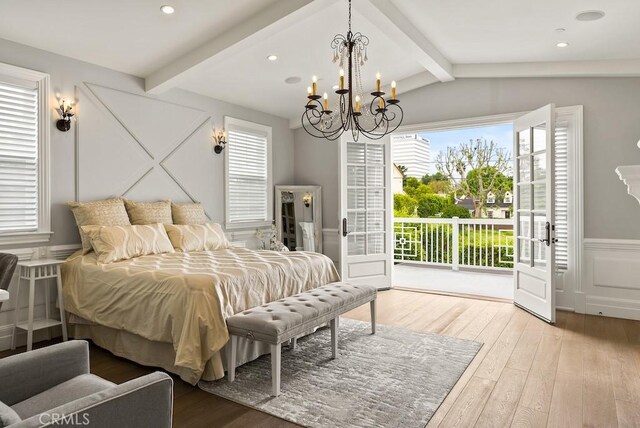 bedroom featuring an inviting chandelier, access to outside, multiple windows, and hardwood / wood-style floors