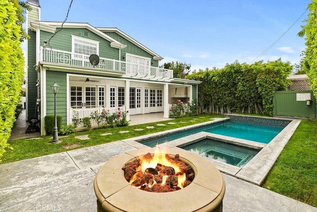rear view of house featuring a fire pit, an outdoor pool, a balcony, a patio, and an in ground hot tub