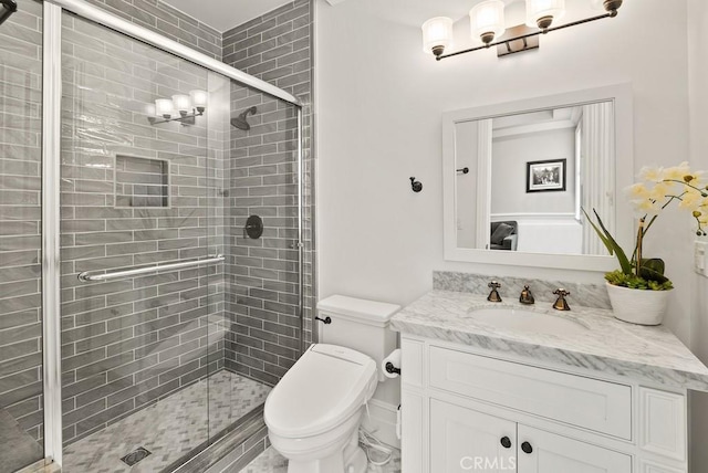 bathroom featuring toilet, vanity, and a shower stall
