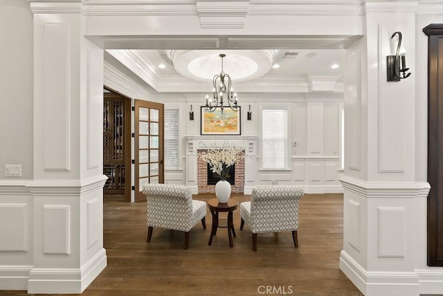 sitting room with plenty of natural light, a decorative wall, a notable chandelier, and wood finished floors
