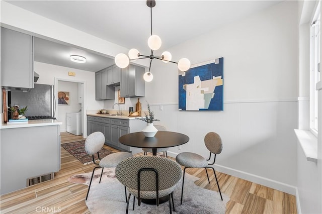 dining room with visible vents, an inviting chandelier, light wood finished floors, and washing machine and dryer
