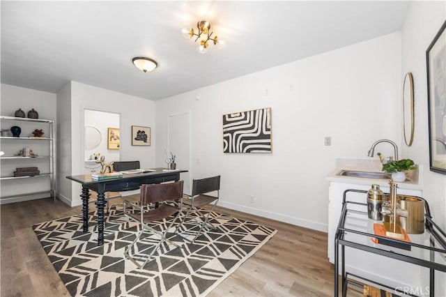 office featuring wood finished floors, baseboards, and a sink