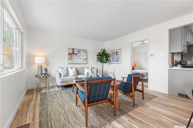 living area with baseboards, visible vents, and light wood-style floors
