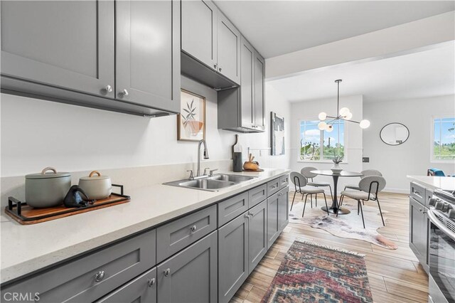 kitchen with gray cabinetry, electric stove, and a sink