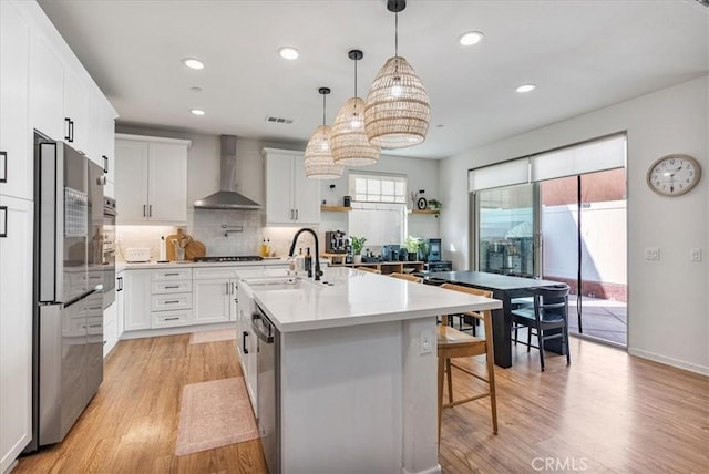 16452 Globetrotter Ave, Chino, CA 91708 - kitchen featuring wall chimney range hood, stainless steel appliances, light wood finished floors, and a sink