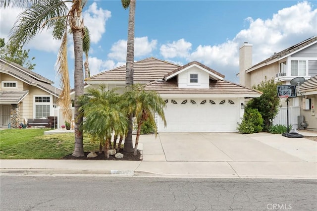 view of front of home with an attached garage, concrete driveway, a tiled roof, and a front yard
