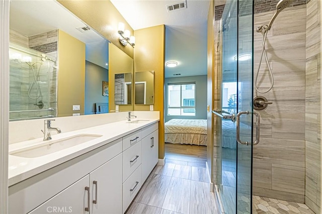 ensuite bathroom featuring double vanity, visible vents, a stall shower, and a sink