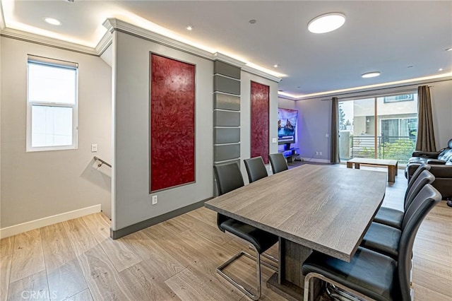 dining space with light wood finished floors, crown molding, and baseboards