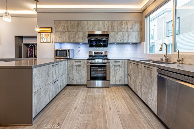 kitchen featuring a sink, decorative backsplash, light wood-type flooring, stainless steel appliances, and a peninsula