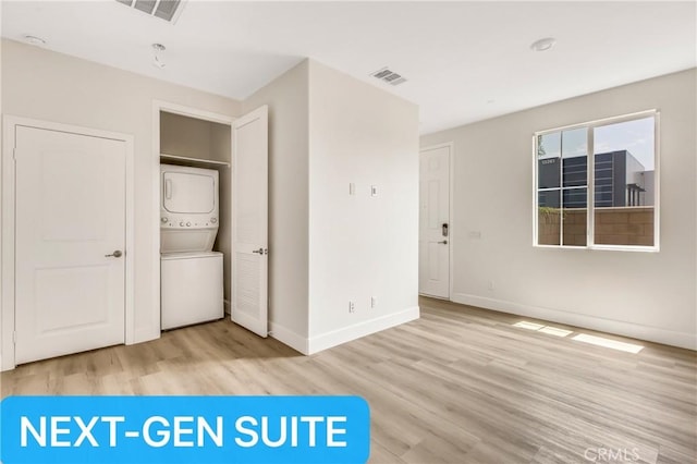 interior space with visible vents, baseboards, stacked washing maching and dryer, and wood finished floors