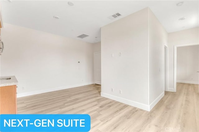 empty room featuring light wood-style floors, baseboards, and visible vents