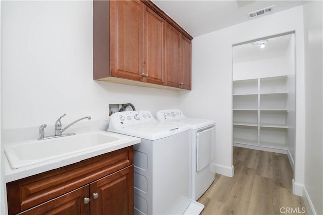laundry room with visible vents, light wood-type flooring, washer and clothes dryer, a sink, and cabinet space