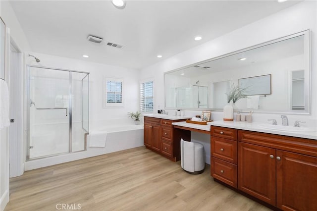 bathroom with vanity, a shower stall, wood finished floors, visible vents, and a garden tub