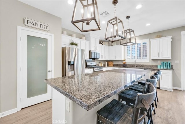 29102 Carrotwood, Lake Elsinore, CA 92530 - kitchen with appliances with stainless steel finishes, a chandelier, light wood-style flooring, white cabinetry, and a center island