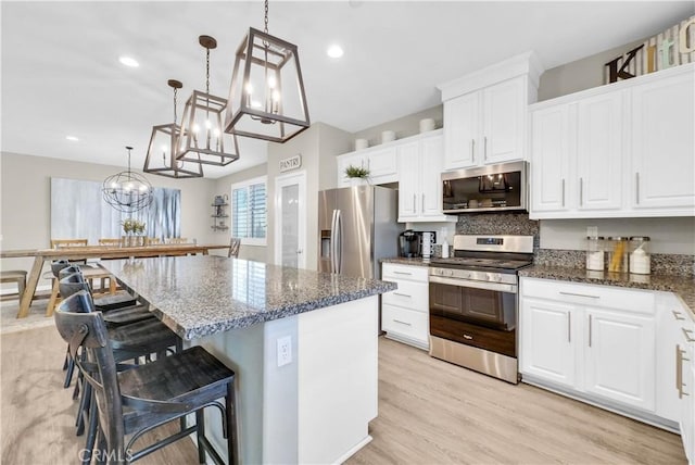 29102 Carrotwood, Lake Elsinore, CA 92530 - kitchen with appliances with stainless steel finishes, a kitchen island, white cabinets, dark stone counters, and a breakfast bar
