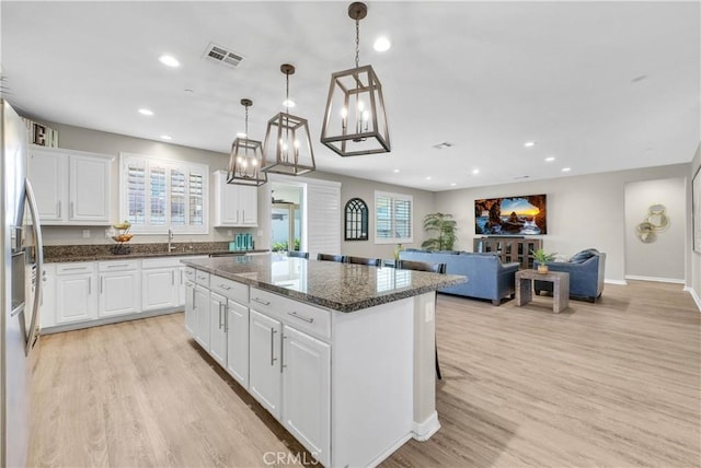 29102 Carrotwood, Lake Elsinore, CA 92530 - kitchen with a kitchen island, stainless steel fridge, a chandelier, white cabinetry, and light wood finished floors