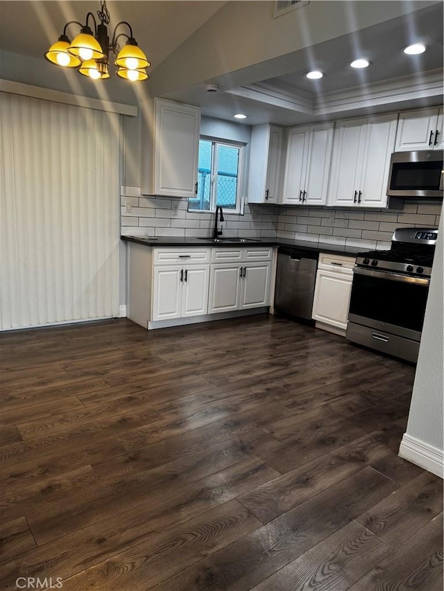 1912 W Quartermaster St, Colton, CA 92324 - kitchen featuring appliances with stainless steel finishes, dark countertops, dark wood-type flooring, tasteful backsplash, and a chandelier