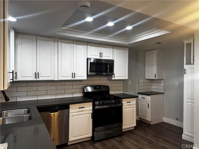 1912 W Quartermaster St, Colton, CA 92324 - kitchen featuring appliances with stainless steel finishes, a tray ceiling, dark wood-style flooring, dark countertops, and crown molding